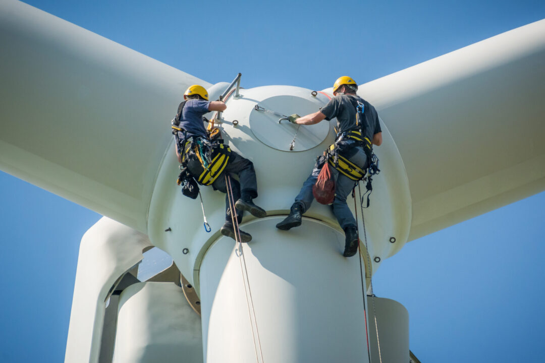 Inspection engineers preparing to rappel down a rotor blade of a